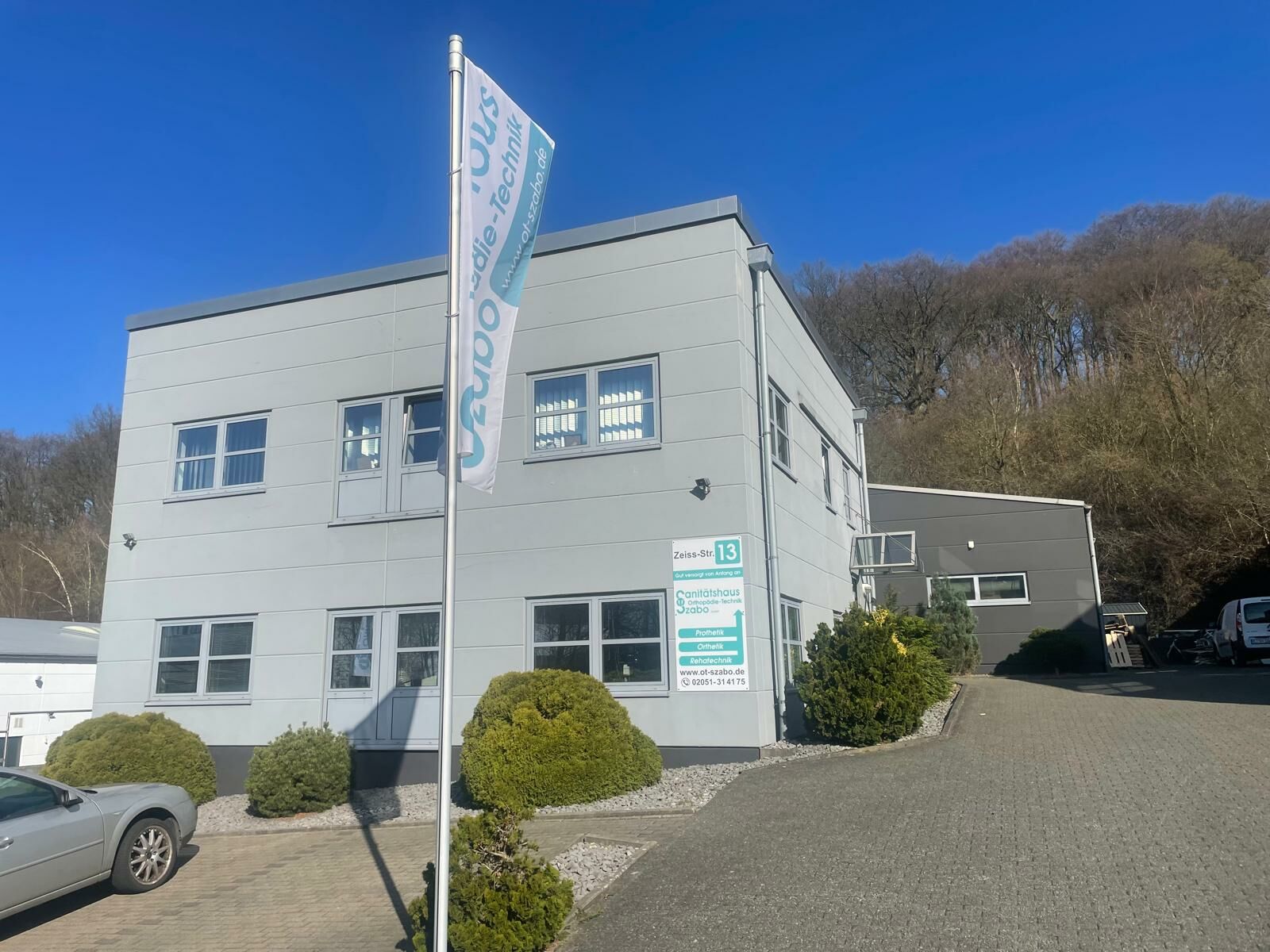 Gebäude des Sanitätshauses Szabo mit Flagge und Parkplatz vor dem Haus